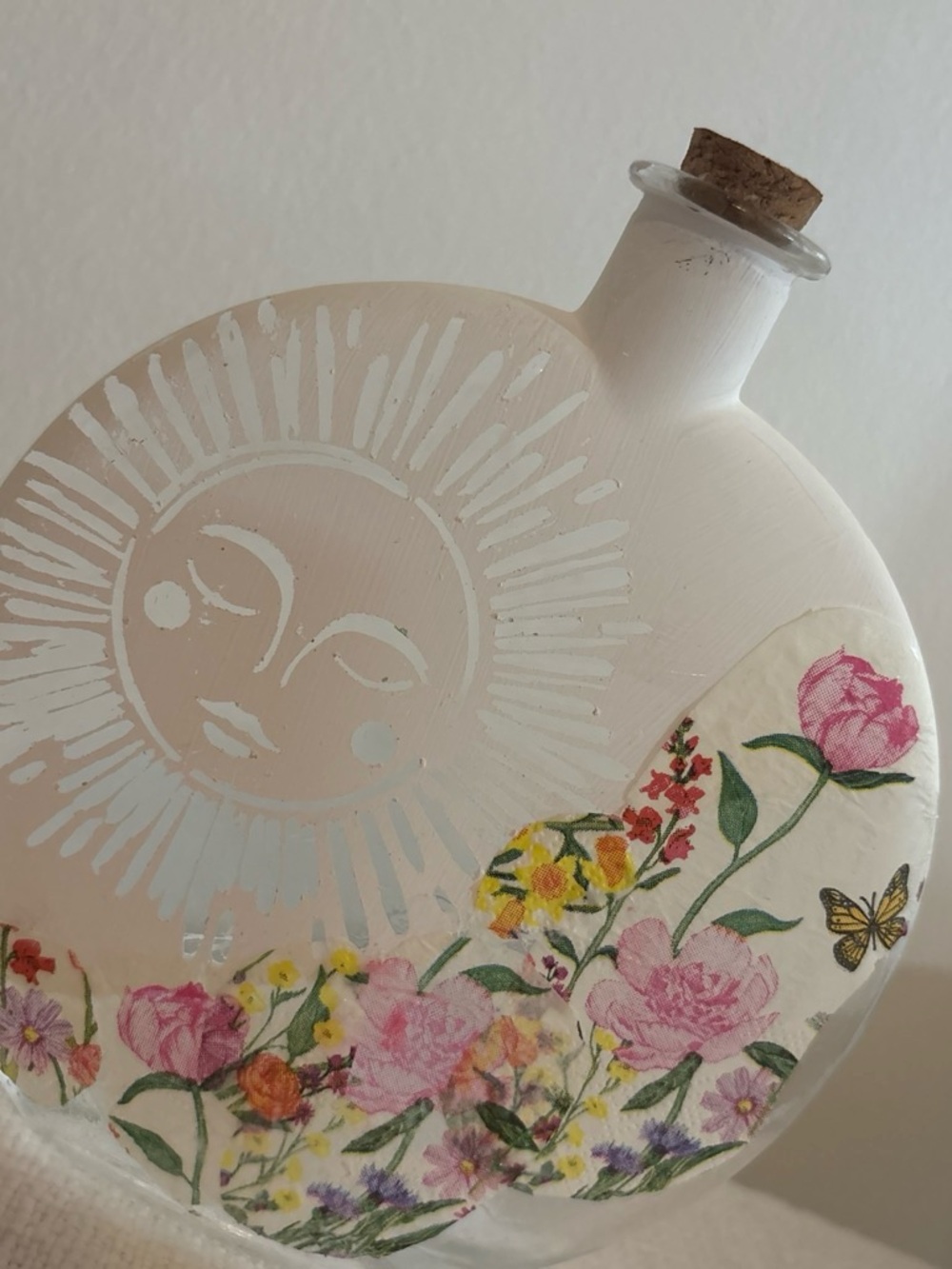 White Floral Sun Decorative Bottle with Cork.  about 8” tall.